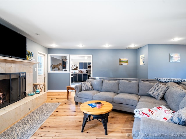 living area with recessed lighting, a fireplace, and wood finished floors