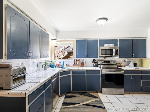 kitchen featuring decorative backsplash, blue cabinets, light tile patterned floors, and stainless steel appliances