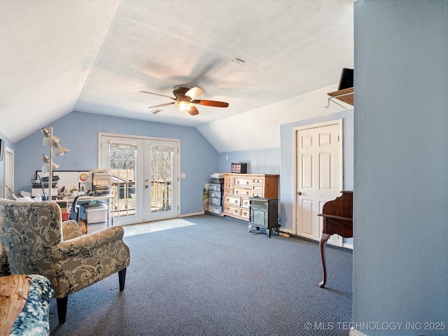 living area featuring carpet, a ceiling fan, visible vents, lofted ceiling, and a textured ceiling