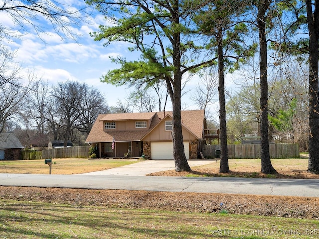 view of front of home with concrete driveway, an attached garage, fence, and stone siding