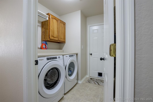 laundry room featuring light tile patterned floors, cabinet space, baseboards, and washing machine and clothes dryer