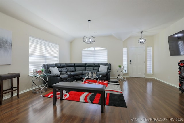 living area with baseboards, a healthy amount of sunlight, wood finished floors, and vaulted ceiling