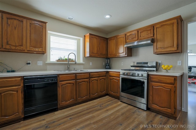 kitchen featuring gas stove, dark wood-style flooring, a sink, black dishwasher, and under cabinet range hood