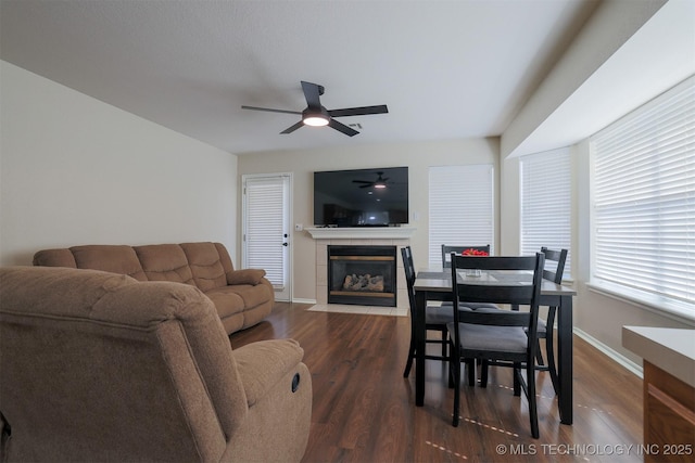 living room featuring a fireplace, wood finished floors, a ceiling fan, and baseboards