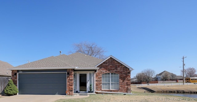 view of front facade featuring fence, concrete driveway, an attached garage, a shingled roof, and brick siding