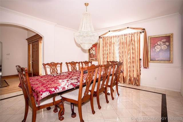 dining area with a notable chandelier, baseboards, arched walkways, and ornamental molding