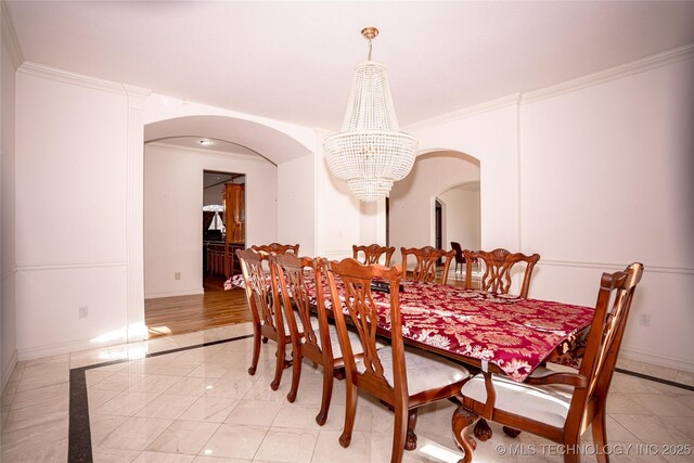 dining space featuring baseboards, arched walkways, a chandelier, and ornamental molding