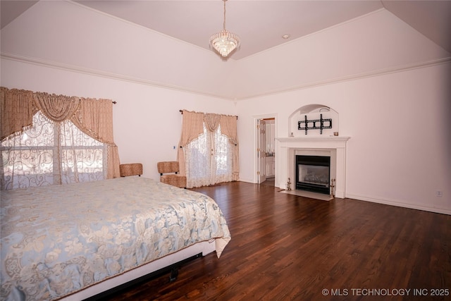 bedroom with lofted ceiling, a fireplace with flush hearth, wood finished floors, and baseboards