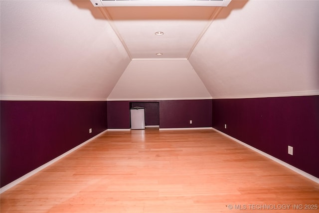 additional living space featuring lofted ceiling, baseboards, and light wood-type flooring