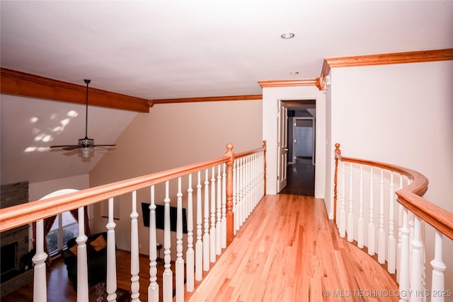 corridor with crown molding, lofted ceiling with beams, an upstairs landing, and light wood-style floors