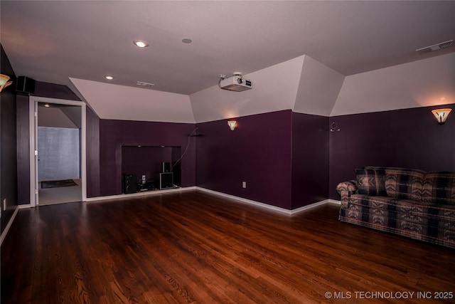 home theater room featuring visible vents, baseboards, wood finished floors, and vaulted ceiling