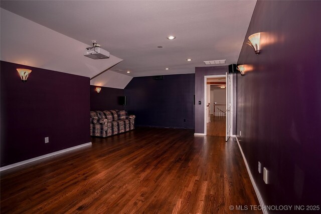 home theater room featuring visible vents, baseboards, dark wood finished floors, vaulted ceiling, and recessed lighting