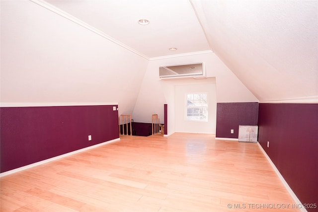 bonus room featuring vaulted ceiling, wood finished floors, baseboards, and a wall mounted AC