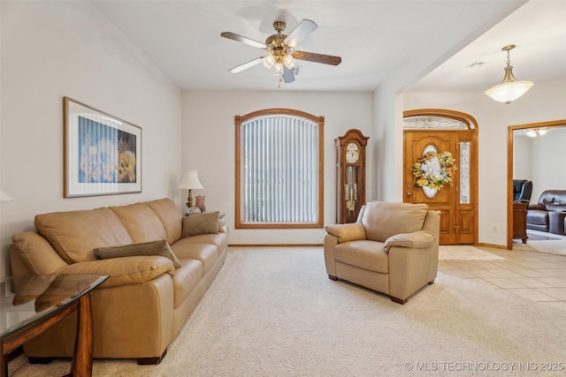 living room with light tile patterned floors, baseboards, light carpet, and ceiling fan