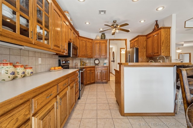 kitchen featuring light tile patterned floors, brown cabinetry, visible vents, and stainless steel appliances