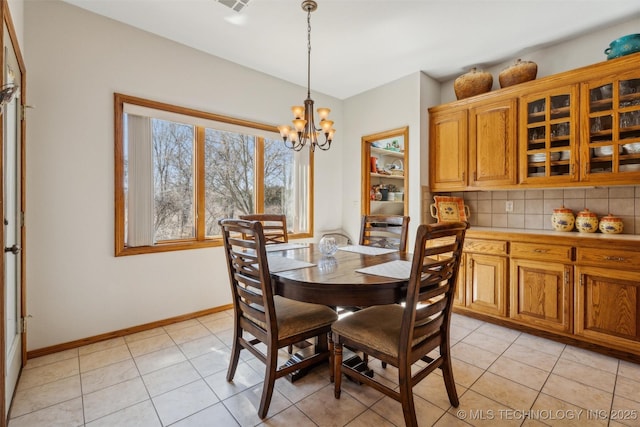 dining space with light tile patterned flooring, a notable chandelier, visible vents, and baseboards