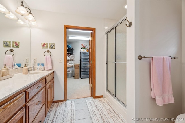 bathroom featuring vanity, tile patterned floors, baseboards, and a stall shower