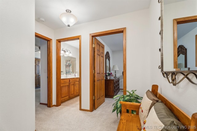 hall featuring light colored carpet and baseboards