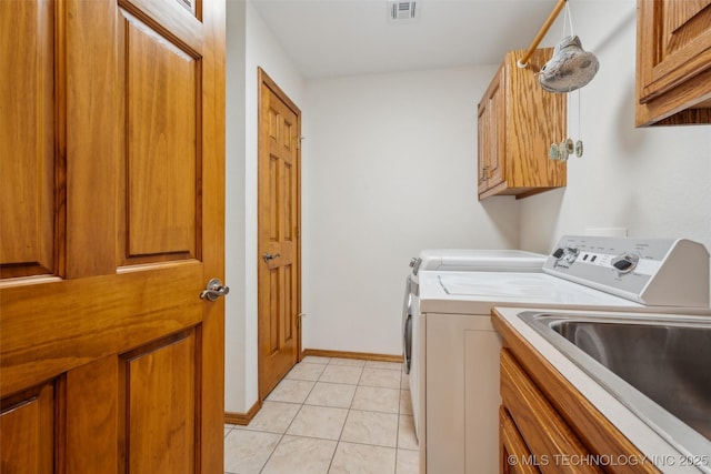 washroom with light tile patterned floors, baseboards, visible vents, cabinet space, and washer and clothes dryer