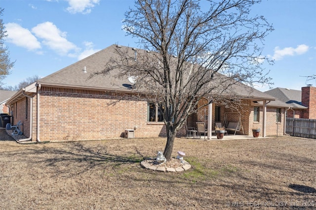 back of property with a patio, a yard, fence, and brick siding