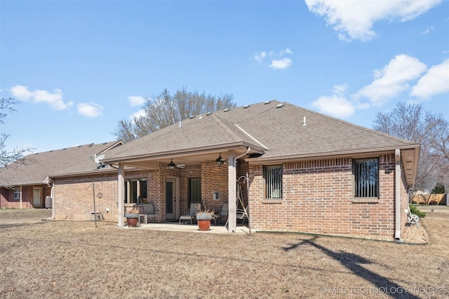 rear view of house with brick siding, roof with shingles, a ceiling fan, and a patio area