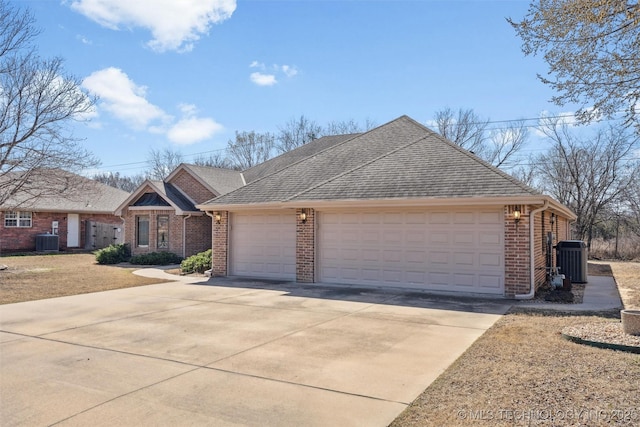 view of front of home with brick siding, a garage, driveway, and central AC