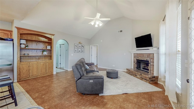 living room with visible vents, a ceiling fan, arched walkways, a fireplace, and baseboards