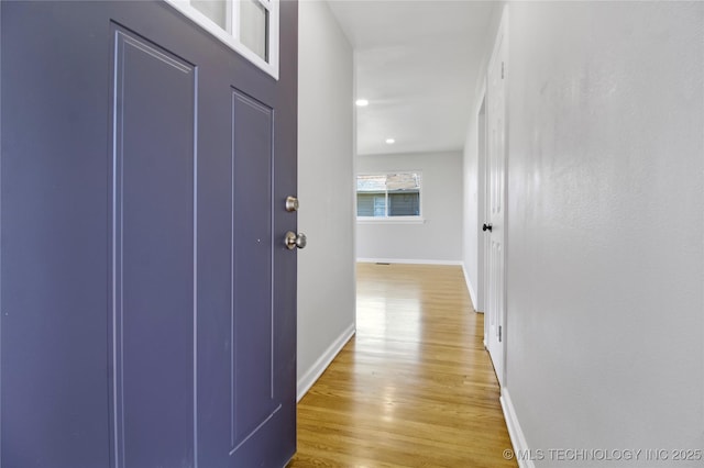 corridor featuring light wood-style flooring and baseboards