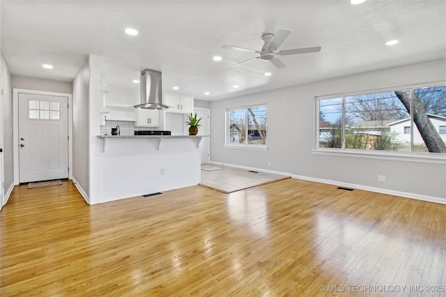 unfurnished living room with a ceiling fan, recessed lighting, light wood-style floors, and baseboards