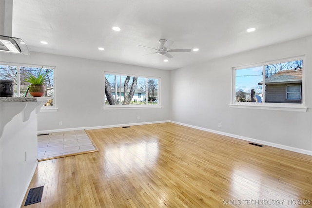 unfurnished living room featuring light wood finished floors, visible vents, and a healthy amount of sunlight