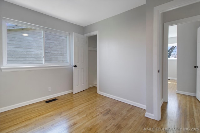 unfurnished bedroom with wood finished floors, visible vents, and baseboards