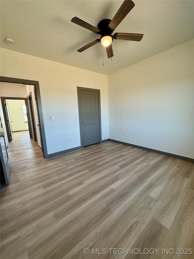 unfurnished bedroom with a ceiling fan, baseboards, and light wood-type flooring