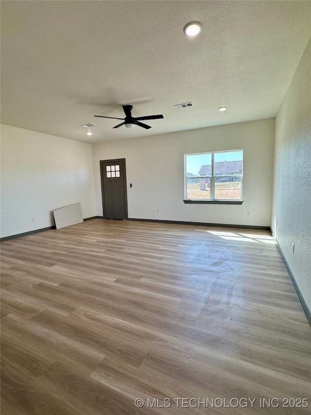 empty room with visible vents, baseboards, ceiling fan, wood finished floors, and a textured ceiling