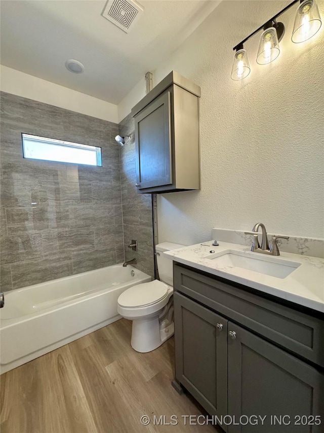 full bathroom with visible vents, toilet, shower / bathing tub combination, wood finished floors, and vanity