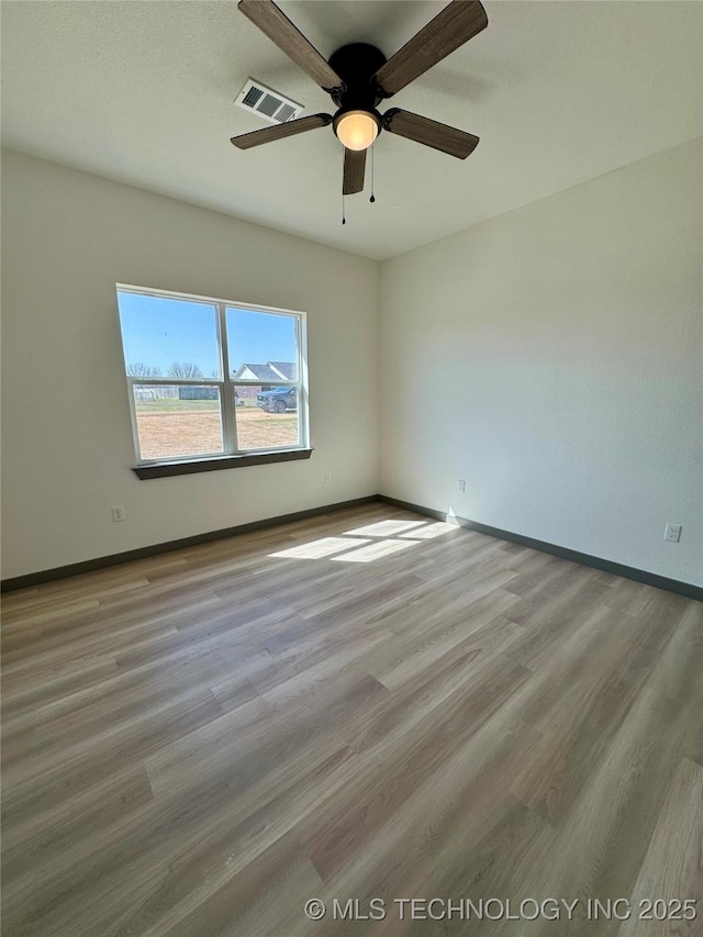 spare room featuring a ceiling fan, wood finished floors, visible vents, and baseboards