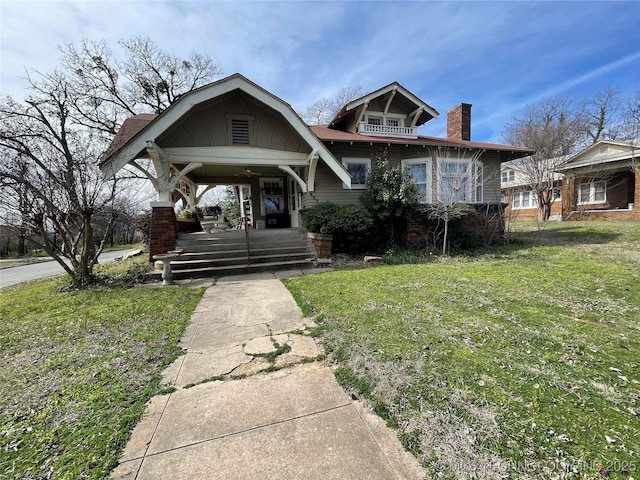 bungalow-style home featuring a front yard, covered porch, and a chimney