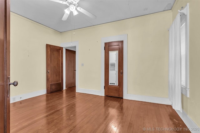 empty room featuring attic access, baseboards, ceiling fan, and wood-type flooring