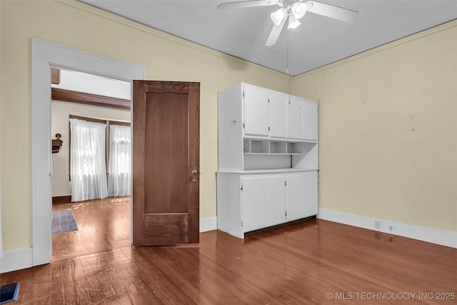 empty room with baseboards, a ceiling fan, and wood finished floors