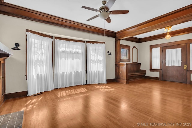 unfurnished living room with crown molding, wood finished floors, a ceiling fan, and baseboards