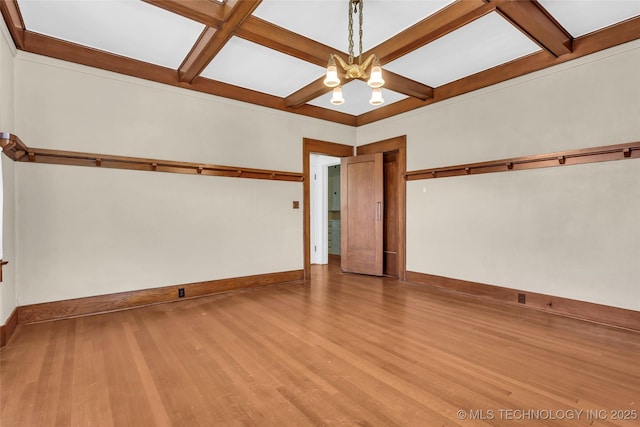 spare room featuring wood finished floors, baseboards, beam ceiling, and coffered ceiling