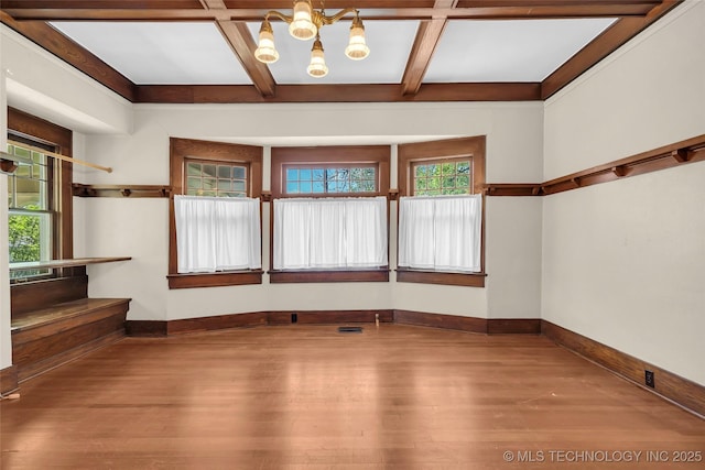 spare room featuring coffered ceiling, wood finished floors, beam ceiling, baseboards, and a notable chandelier