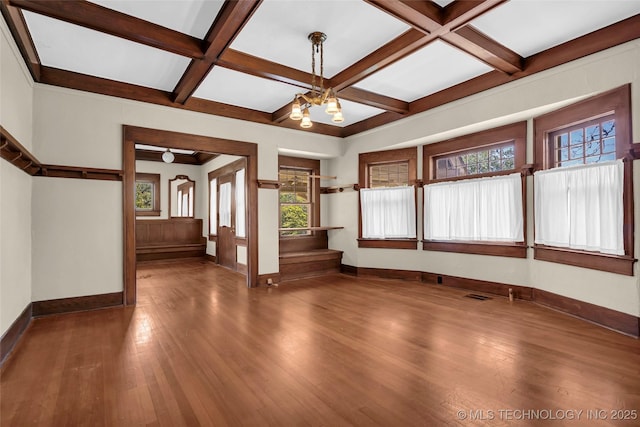 unfurnished living room with coffered ceiling, wood finished floors, and baseboards