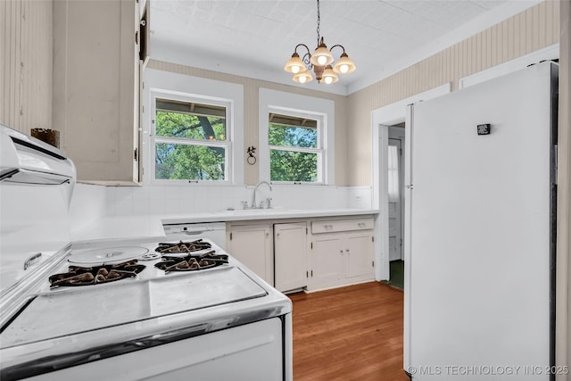 kitchen featuring white cabinets, a sink, white appliances, light wood-type flooring, and a notable chandelier