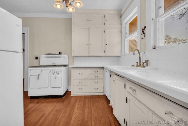 kitchen featuring white cabinets, backsplash, a sink, washer / dryer, and white appliances