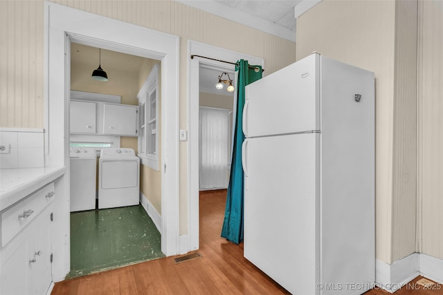 kitchen featuring light countertops, wood finished floors, visible vents, freestanding refrigerator, and separate washer and dryer