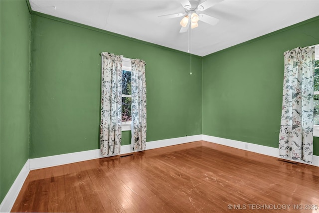unfurnished room featuring wood finished floors, visible vents, baseboards, and ceiling fan
