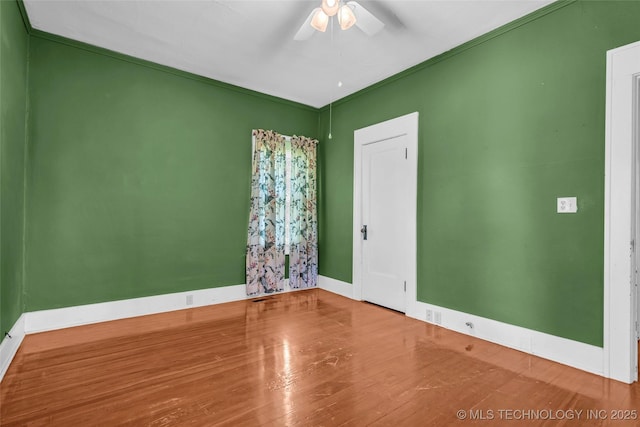 empty room featuring baseboards, a ceiling fan, and wood finished floors