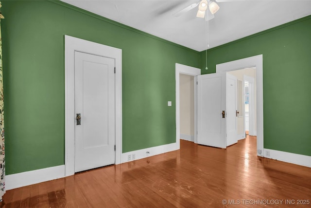 unfurnished bedroom featuring wood finished floors, baseboards, and ceiling fan