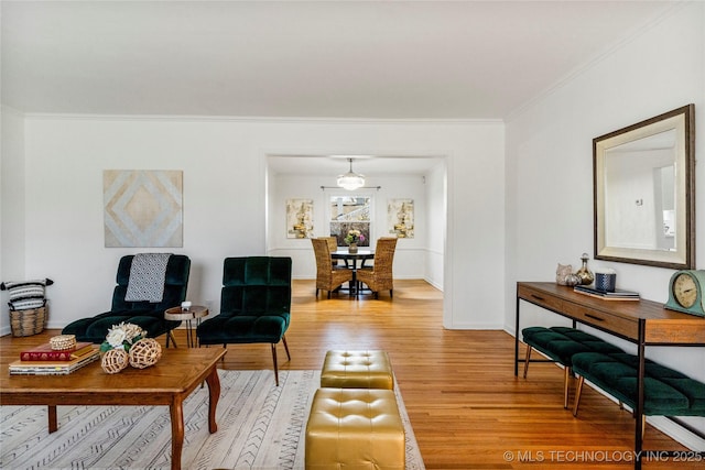 living area with baseboards, light wood-style floors, and ornamental molding