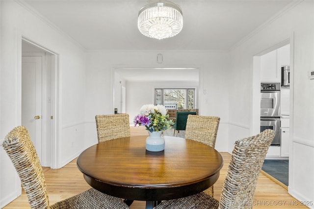 dining space featuring an inviting chandelier, light wood-style flooring, and crown molding